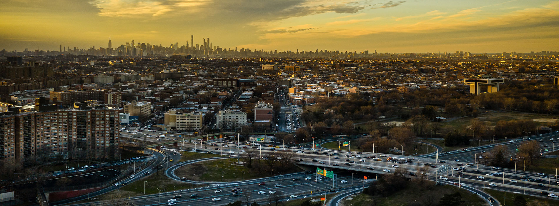 The image depicts a cityscape with buildings and roads at sunset, viewed from an elevated perspective.