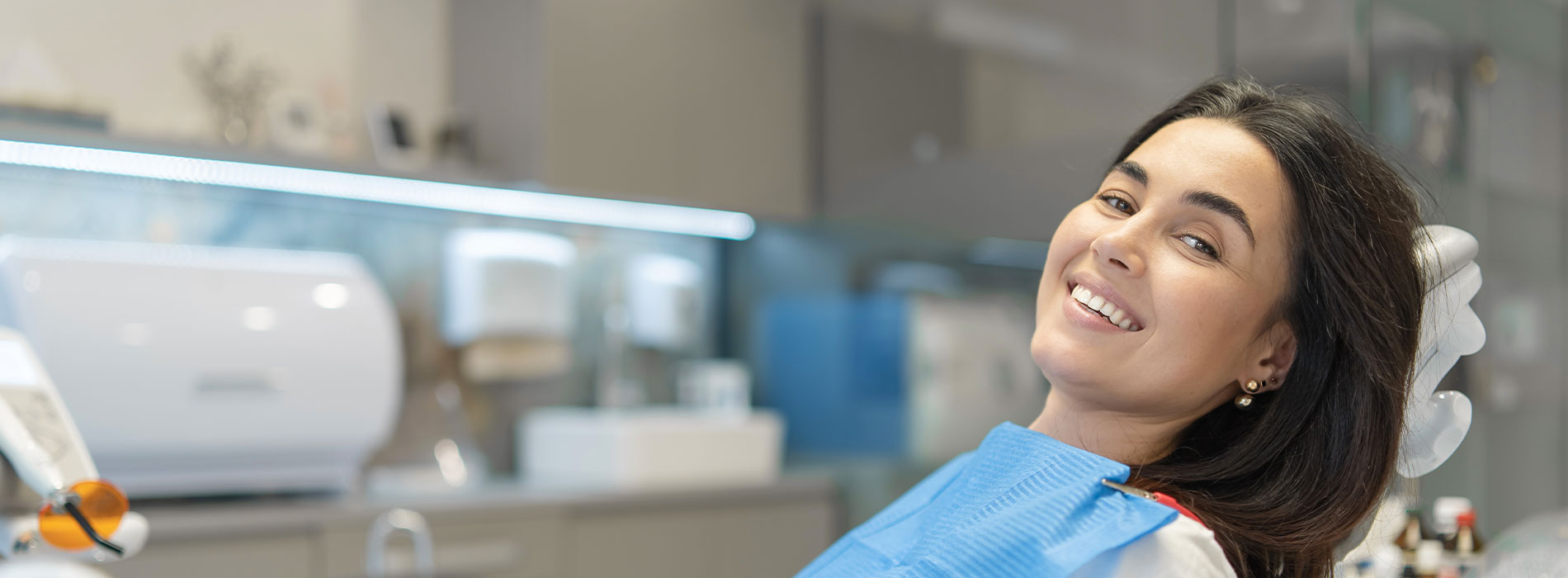 A well-lit reception area with a desk, computer monitor, and potted plant.