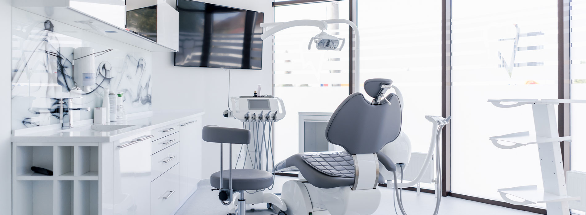 The image shows a modern dental clinic interior with various pieces of equipment, including a dental chair and an X-ray machine.