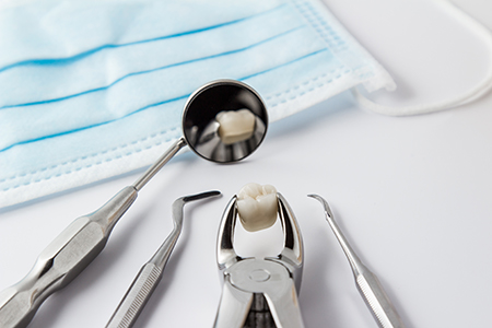 The image shows dental tools with a focus on a toothbrush with toothpaste applied and a dental mirror reflecting this activity, all set against a blue surgical drape background.