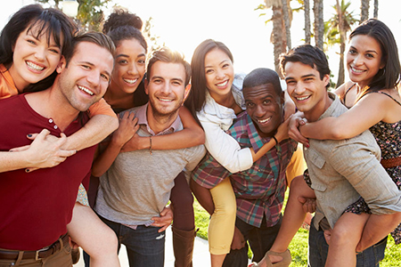A group of young adults posing together outdoors with smiles on their faces.