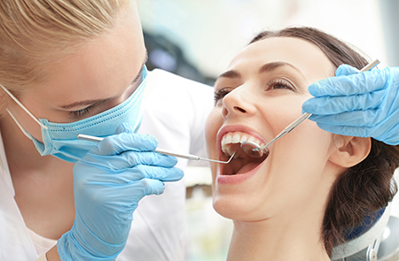 The image shows a dental professional performing a procedure on a patient s mouth, with the patient smiling at the camera while being attended to by the professional.